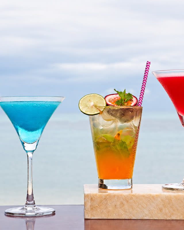 Colourful cocktails on a ledge with the sea behind