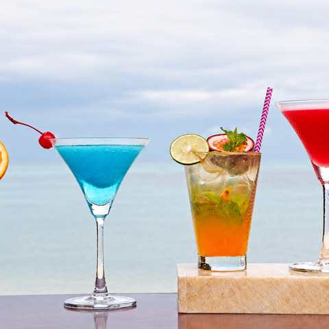Colourful cocktails on a ledge with the sea at the horizon