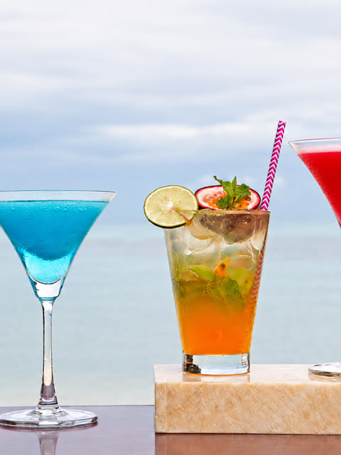 Colourful cocktails on a ledge with the sea behind