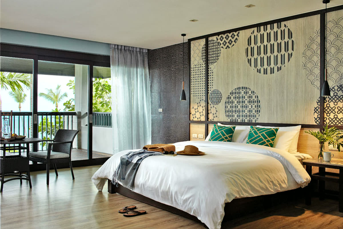 King bed in front of a patterned timber panel, with sliding doors to a balcony