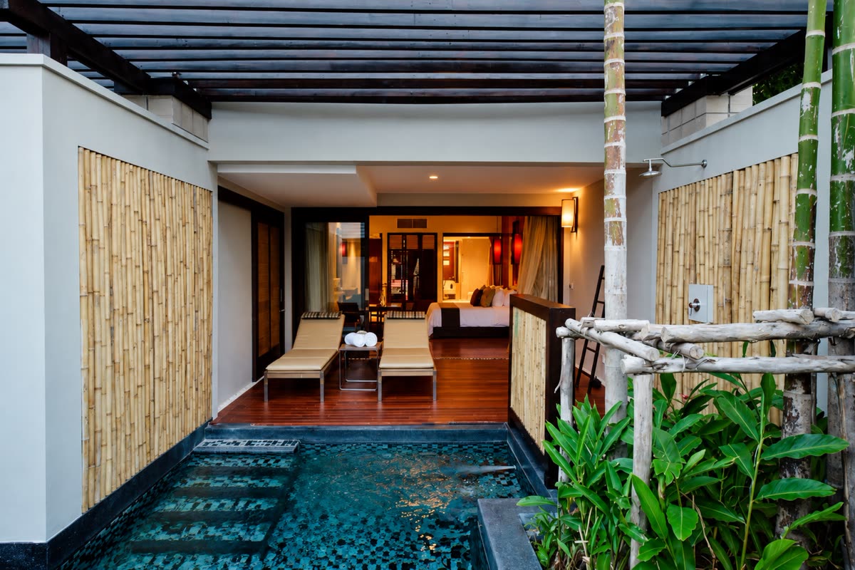Terrace sun loungers and a tiled pool below a timber pergola, with the bed visible inside