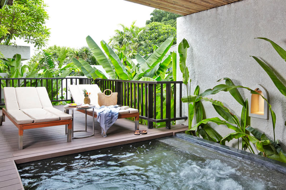 Terrace with two sun loungers beside a bubbling Jacuzzi among banana leaves