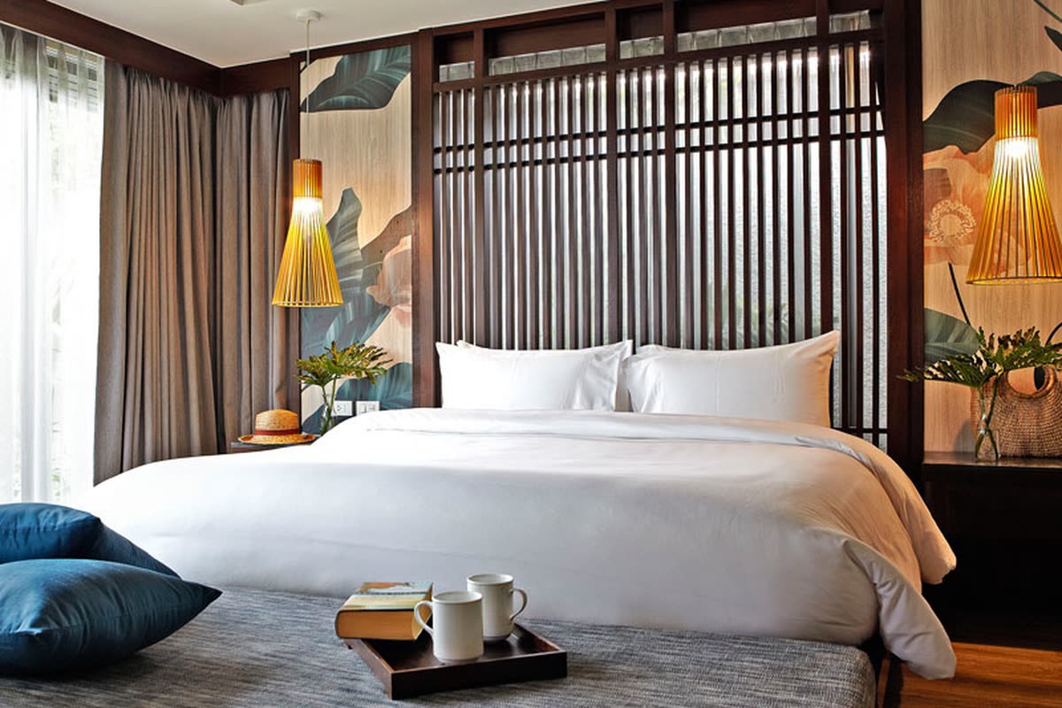 King bed with a timber screen headboard and warm woven lamps