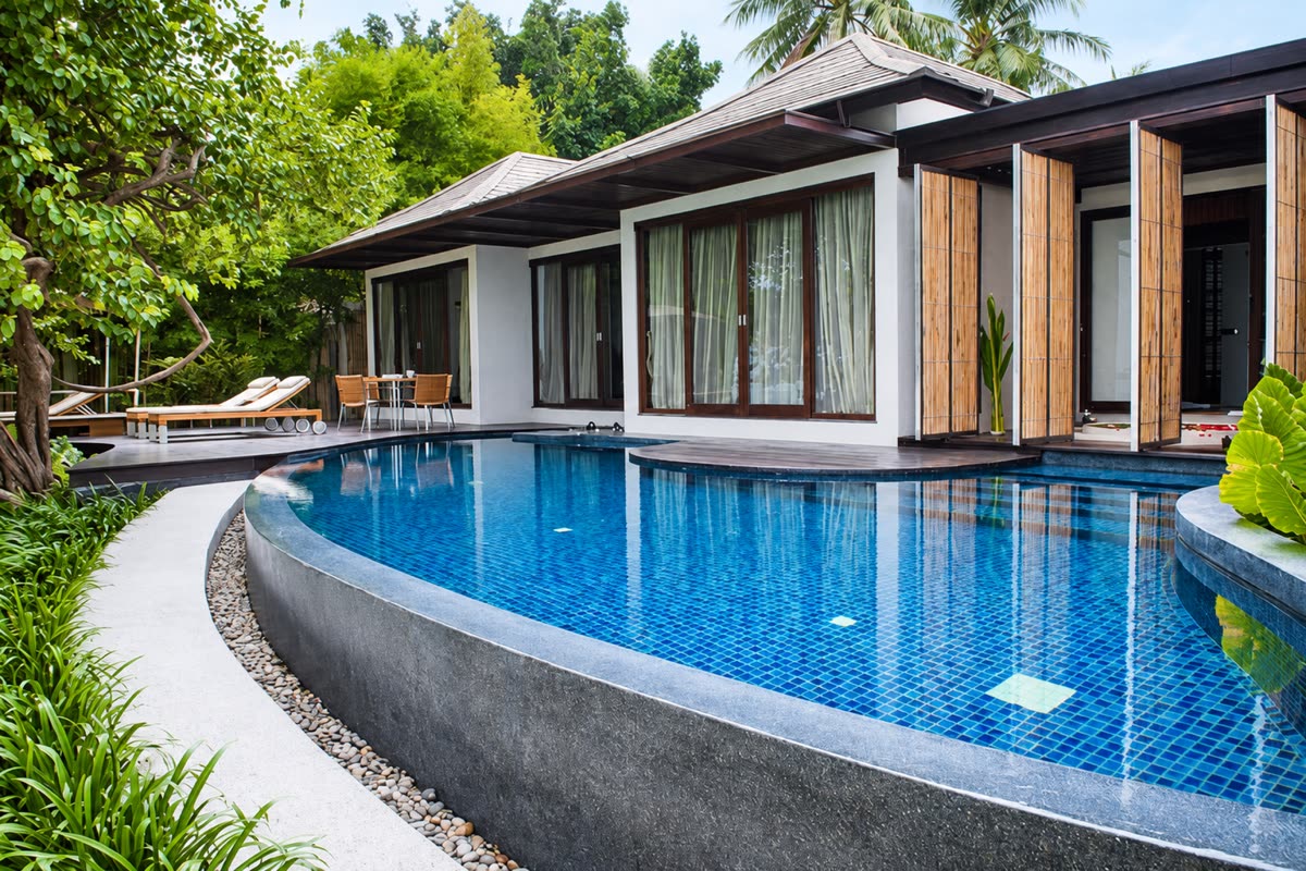 Villa with shuttered timber doors beside a curved blue-tiled pool