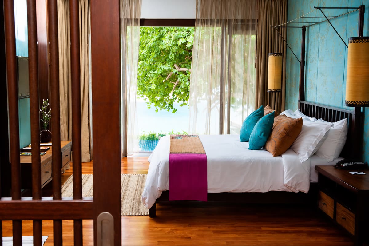 Bedroom with teal and copper cushions and a door open to the garden